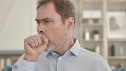 Mature Man Coughing Indoors on a Couch