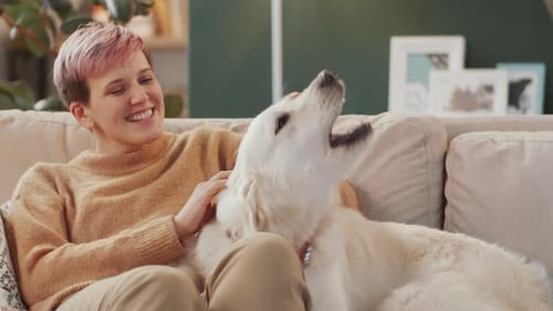 Happy Woman Cuddling Golden Retriever on Sofa