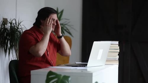 Man working at home office at laptop and talking by web camera