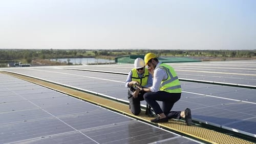 4K Professional engineer using tablet maintaining solar cell panels together on building rooftop.