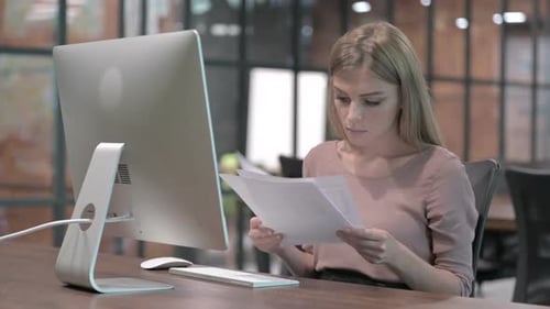 Ambitious Woman Reading Document on Office Desk