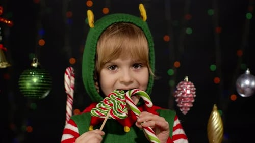 Joyful Child in Elf Costume Eating Lollipops