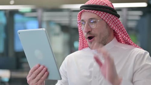Man In Headscarf Talking On Tablet In Office