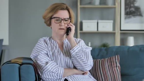 Woman Talks on Smartphone While Sitting on Sofa