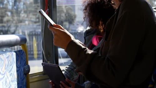 People with devices ride a bus