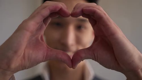 Handsome Asian Man Shows Heart Gesture with Hands Smiling