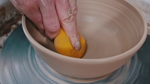 Potter Smoothing Clay Bowl on Pottery Wheel