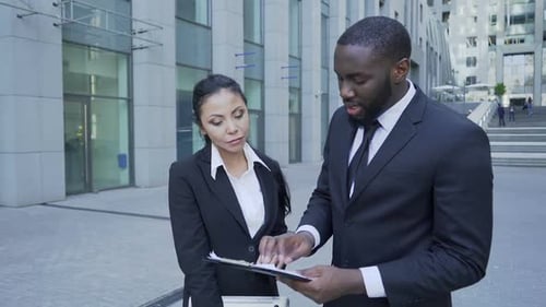 El jefe comenta sobre archivos a un asistente personal cerca de la oficina, documentos importantes