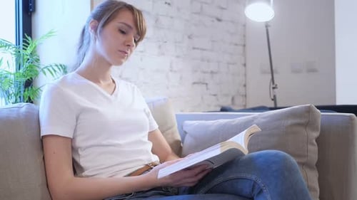 Woman Reading a Book on a Sofa at Home