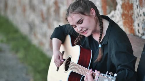 Cute Girl Plays the Guitar in the Park
