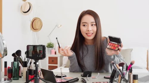 Joven hermosa mujer asiática influencer de belleza profesional haciendo un tutorial de maquillaje cosmético en línea