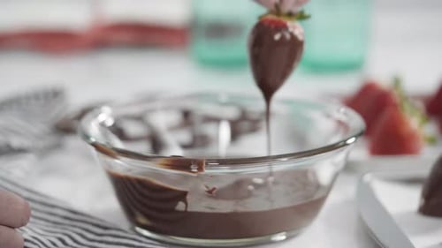 Step by step. Dipping organic strawberries into a bowl with melted chocolate to prepare chocolate co