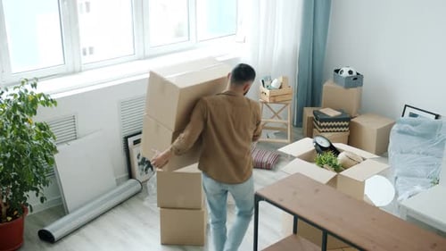 High Angle View of Young Mover Carrying Cardboard Boxes Into Modern New Apartment