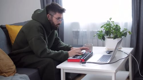 Man plays synthesizer at home on his laptop