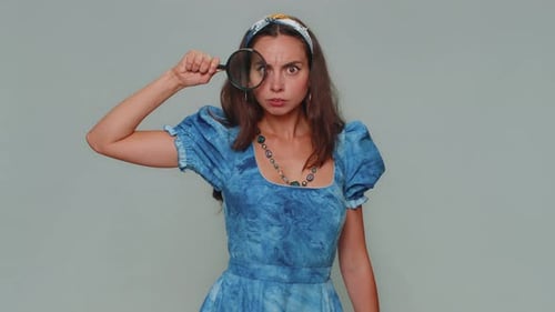 Chercheur scientifique femme tenant une loupe près du visage regardant la caméra avec un grand œil zoomé