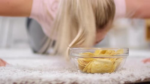Woman Exercising at Home and Eating Chips