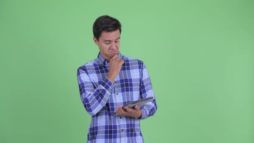 Young Adult Using Tablet Against Green Screen