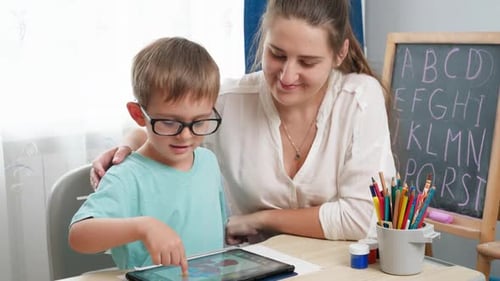 Boy Uses Tablet Computer with Teacher at Table