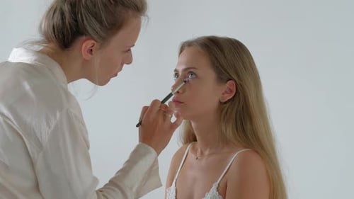 Woman Applying Makeup to a Model in Studio
