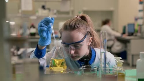 Woman Scientist Conducts Experiment in Bright Lab