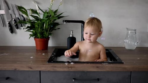 Baby Bathing in Bubbles in a Kitchen Sink