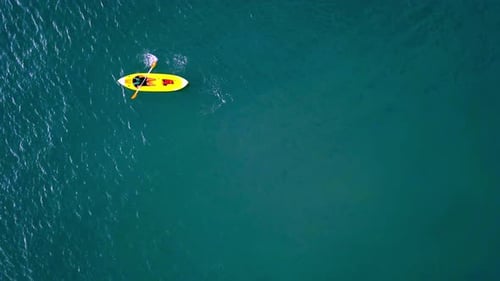 Aerial top down shot of an unrecognizable man rowing on a kayak on turquoise color water