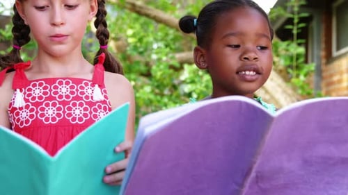Schoolgirls reading book in campus at school