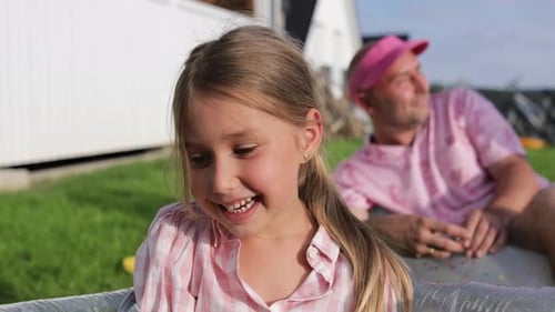 Smiling girl looking at camera, father in the background