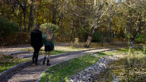 Passanten im Park am Herbsttag Liebendes Paar geht in der Nähe des Teiches spazieren
