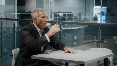 Mature Businessman Drinking Coffee From Cup Sitting In Office Center