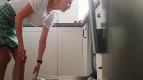 Woman Loading Dishes Into Dishwasher in Modern Kitchen