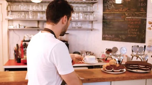 Handsome Barista Wipes Counter in Cafe, Smiling