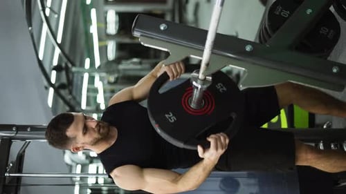 Male Athlete Preparing for Intensive Workout Loading Heavy Plates on Barbell