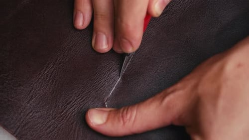 Nahaufnahme Die Hand des Mannes schneidet Ledergewebe mit Spezialmesser. Handwerkliche Produktion. Filmmusik Licht. Macro