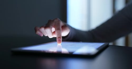 Frau berührt abends den Tablet-Computer zu Hause mit dem Finger