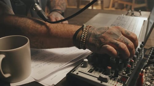 Hand Adjusting Audio Mixer Console in Dimly Lit Studio
