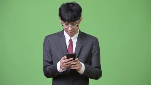 Young Adult Using Phone Against Green Background