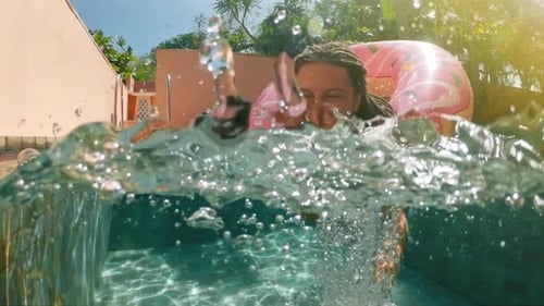 Woman with Sunglasses in Blue Bikini Lying in Inflatable Pink Donut Float in Pool on Sunny Summer
