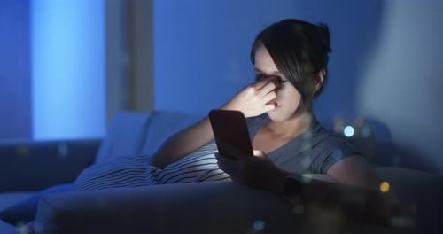 Woman Uses Smartphone on Sofa at Night