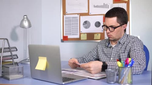 Boss Checking the Documents Sitting at the Desk Where the Laptop Stands