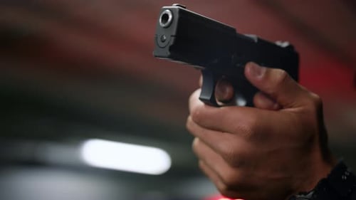 Hand Holding Gun in Dark Urban Setting