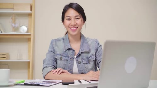 Asia business woman feeling happy smiling and looking to camera while relax at home office.