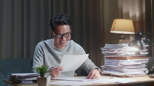 Smiling Asian Man Enjoys Working With Documents At Home