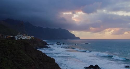 Silhouette Cliffs mit Gebäuden der kleinen tropischen Stadt Almaciga im Meer, die den Sonnenuntergang enthüllen