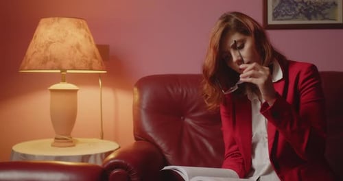 Woman Reading Book on Red Couch Indoors