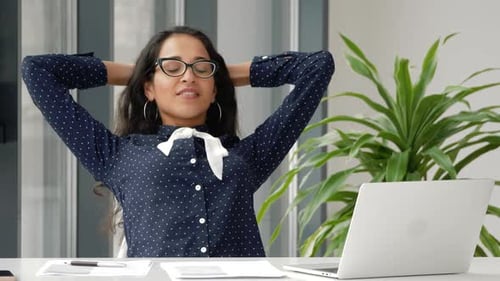 Bonne femme métisse se reposant les yeux fermés et les mains croisées derrière la tête, appréciant rel