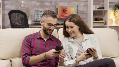Smiling Couple Sharing Mobile Phone Content at Home