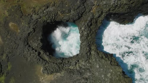 Aerial Footage of Surge of Waves at a Rocky Coast with Clear Blue Water