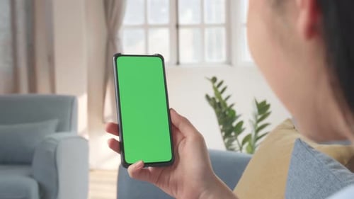 Female Using Smartphone With Green Screen In Living Room