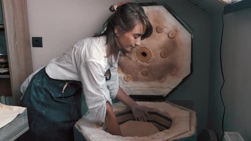 Woman placing pottery in a kiln